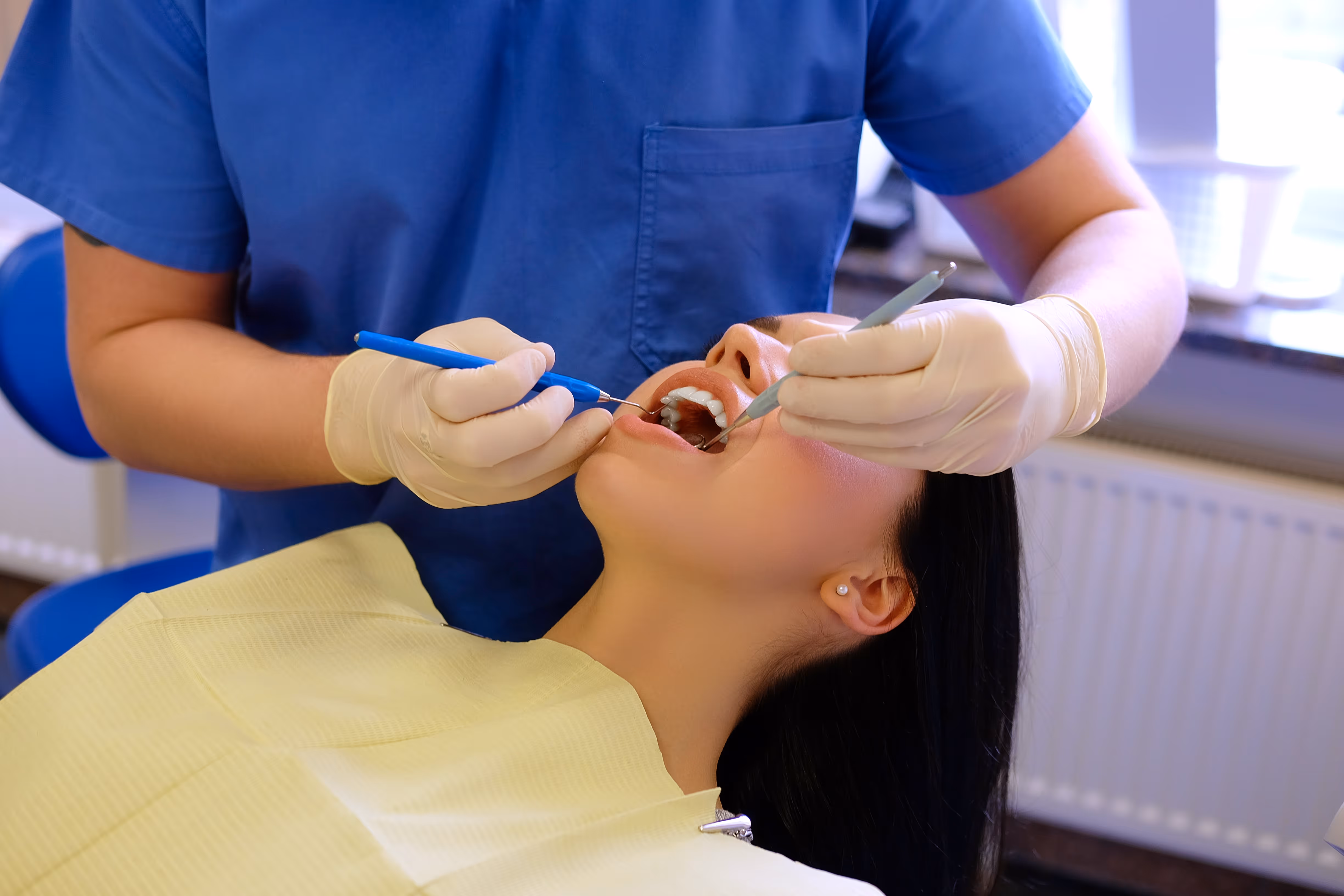 A dental hygienist performing clinical work with instruments